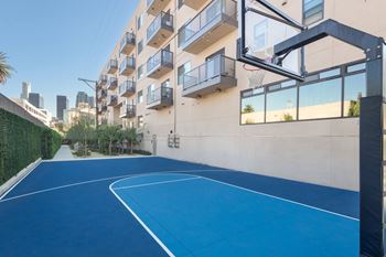 A basketball court is located on the balcony of an apartment building.